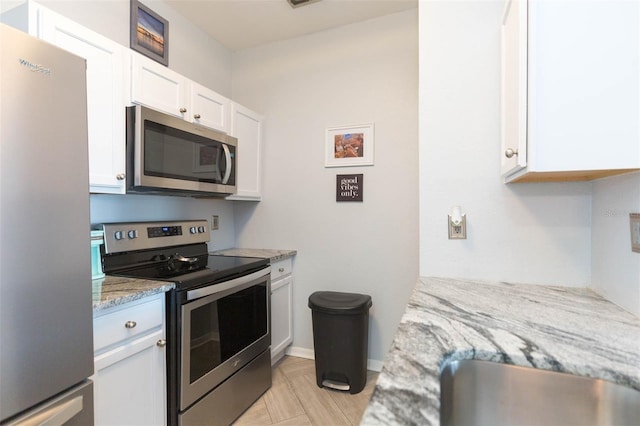 kitchen with light stone countertops, appliances with stainless steel finishes, and white cabinets