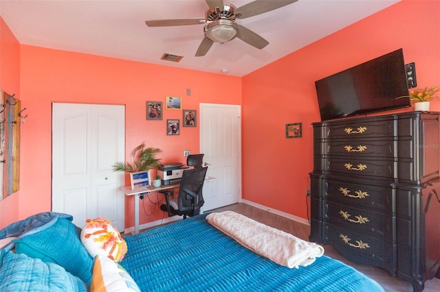 bedroom featuring wood finished floors, visible vents, baseboards, a ceiling fan, and a closet