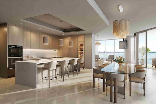 kitchen with dobule oven black, a large island, modern cabinets, and a tray ceiling