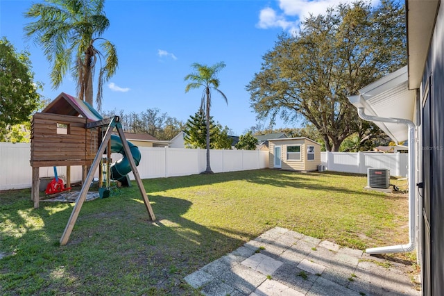 view of yard with an outbuilding, cooling unit, a playground, and a fenced backyard