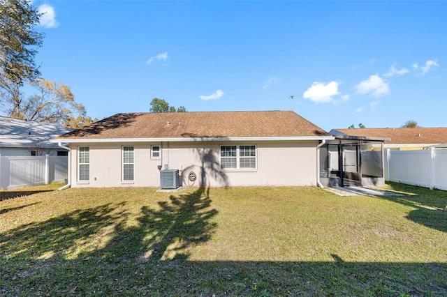 rear view of house featuring cooling unit, a lawn, roof with shingles, and a fenced backyard