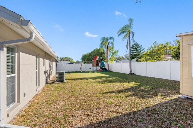 view of yard featuring central AC unit, a playground, and a fenced backyard