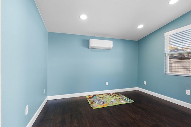 empty room featuring dark wood finished floors, an AC wall unit, recessed lighting, and baseboards