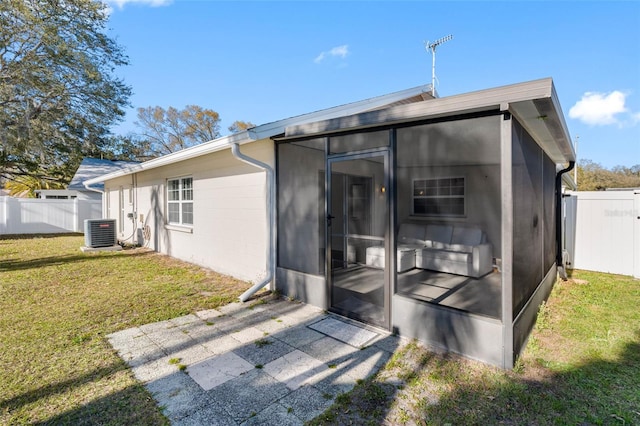 rear view of house featuring central air condition unit, fence, a yard, and a sunroom