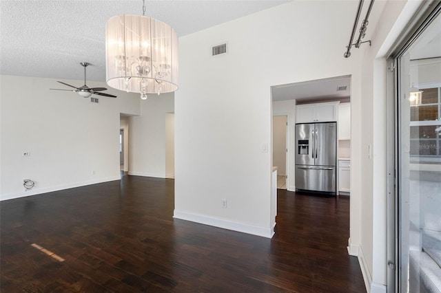 spare room featuring visible vents, ceiling fan with notable chandelier, baseboards, and dark wood-style flooring