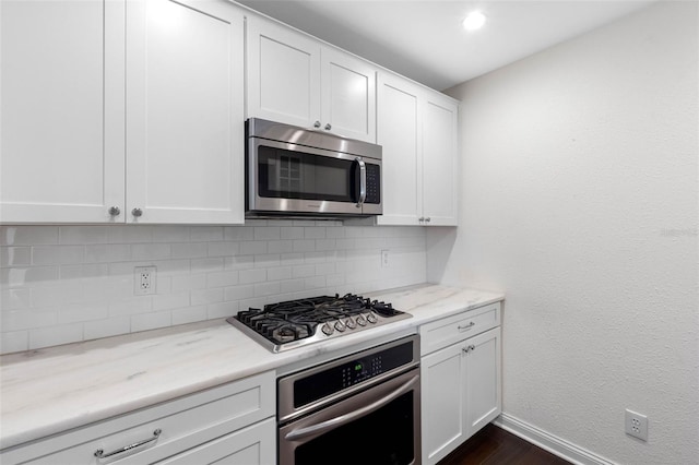 kitchen featuring light stone countertops, baseboards, stainless steel appliances, white cabinets, and backsplash