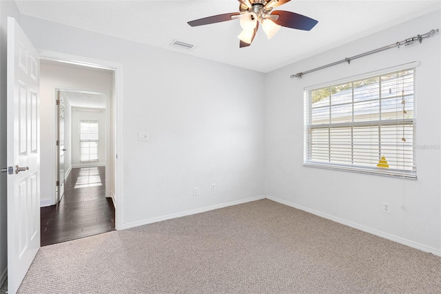 carpeted spare room featuring baseboards, visible vents, and ceiling fan