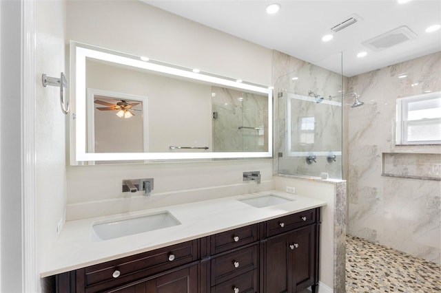 full bath with a marble finish shower, visible vents, double vanity, and a sink