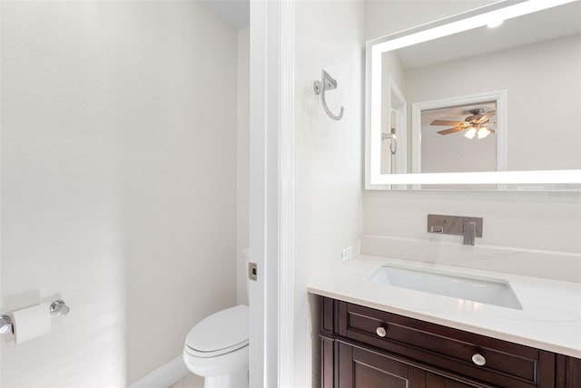 bathroom featuring baseboards, toilet, vanity, and ceiling fan