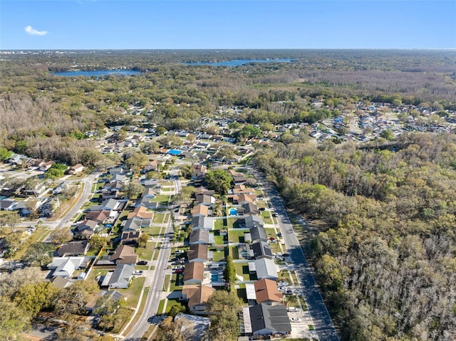 drone / aerial view with a residential view, a view of trees, and a water view