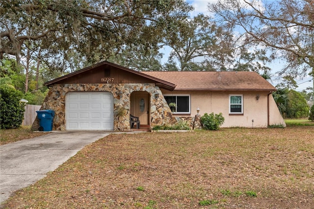 ranch-style home featuring an attached garage, stone siding, driveway, stucco siding, and a front yard