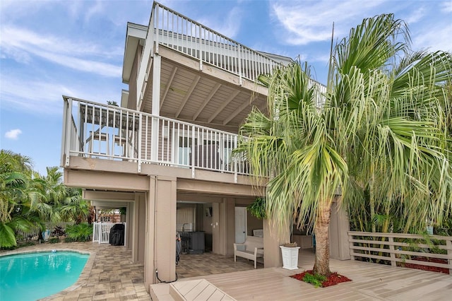 17404 1st St E, Redington Shores, FL 33708 - rear view of house with a balcony, an outdoor pool, a patio area, and a deck