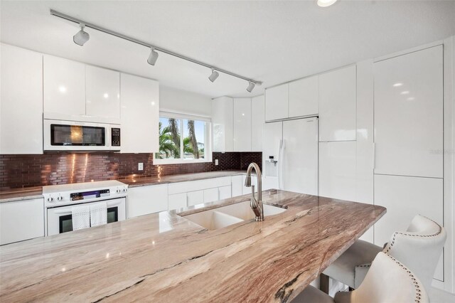 17404 1st St E, Redington Shores, FL 33708 - kitchen featuring white appliances, a sink, modern cabinets, white cabinetry, and a kitchen bar