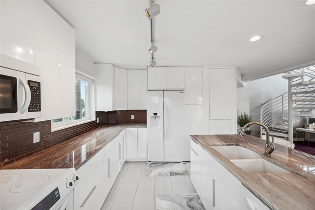 17404 1st St E, Redington Shores, FL 33708 - kitchen with white appliances, a sink, white cabinets, decorative backsplash, and dark stone countertops