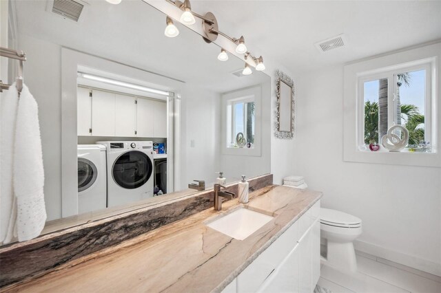 17404 1st St E, Redington Shores, FL 33708 - bathroom featuring independent washer and dryer, baseboards, toilet, tile patterned flooring, and vanity