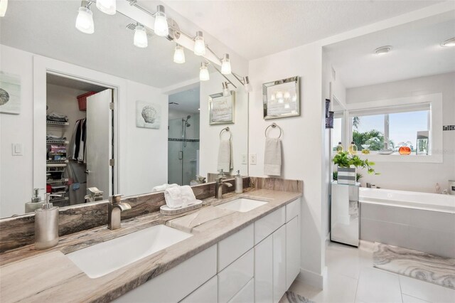 17404 1st St E, Redington Shores, FL 33708 - full bathroom featuring a shower stall, double vanity, a spacious closet, tile patterned floors, and a garden tub