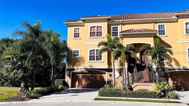 mediterranean / spanish-style home with stucco siding, concrete driveway, an attached garage, and a tile roof