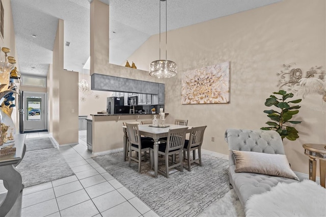 dining area with light tile patterned floors, baseboards, an inviting chandelier, a textured ceiling, and high vaulted ceiling