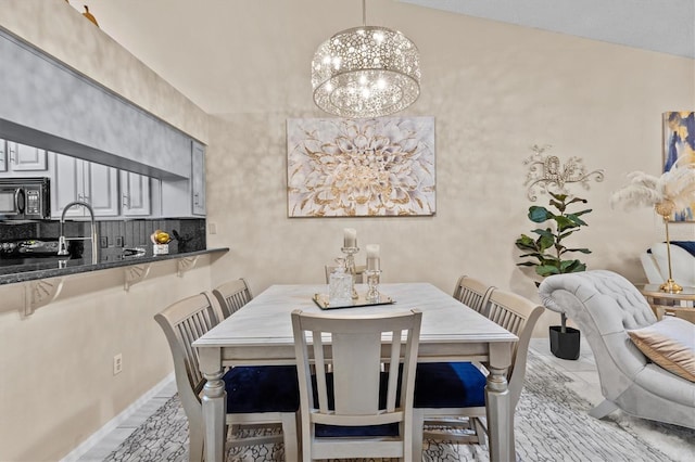 dining room with a chandelier, lofted ceiling, and baseboards