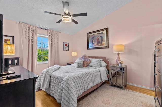 bedroom featuring vaulted ceiling, a textured ceiling, and light wood-style flooring