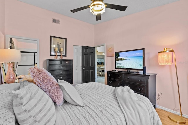 bedroom featuring a ceiling fan, wood finished floors, visible vents, and baseboards