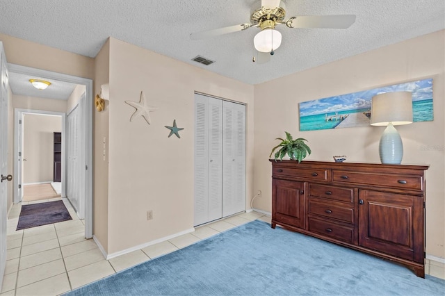 bedroom featuring a closet, visible vents, a textured ceiling, and light tile patterned floors