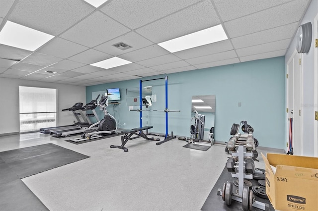 exercise room with a paneled ceiling, baseboards, and visible vents