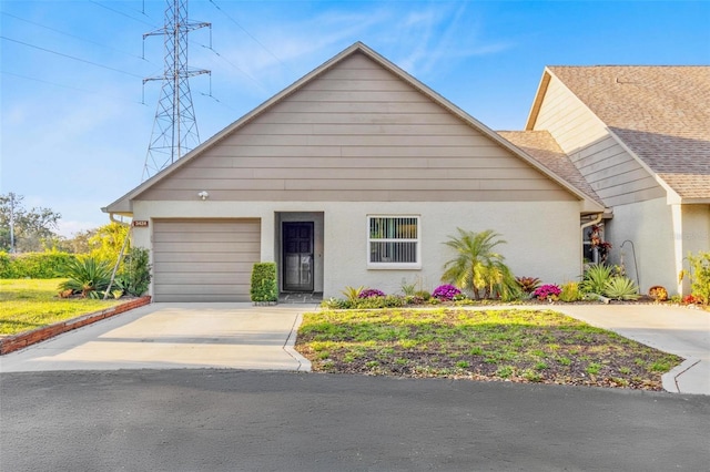 view of front of property with a garage, concrete driveway, a shingled roof, and stucco siding