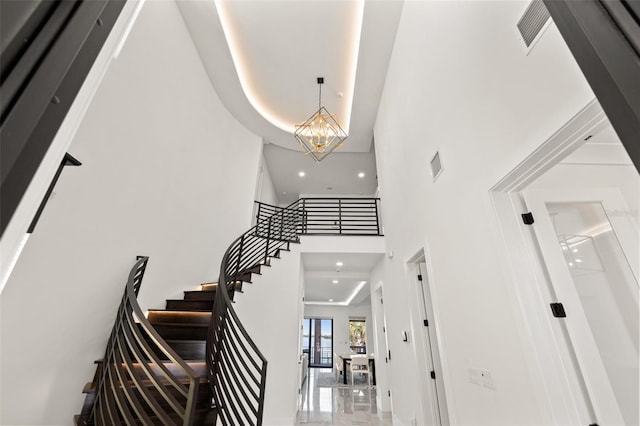 stairs featuring recessed lighting, visible vents, an inviting chandelier, and a towering ceiling