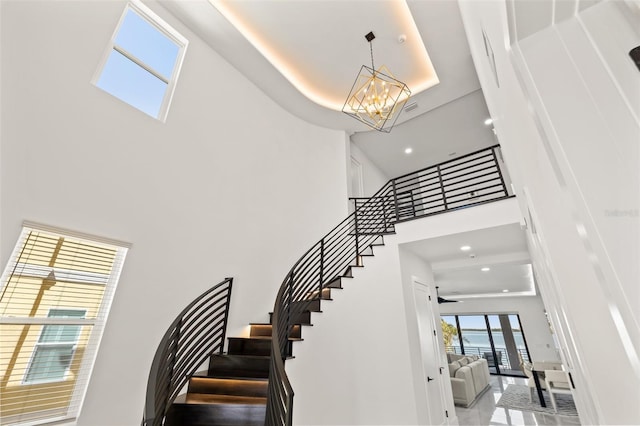 stairway featuring visible vents, a towering ceiling, recessed lighting, a raised ceiling, and a chandelier