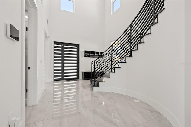 entryway with baseboards, a high ceiling, marble finish floor, and stairs