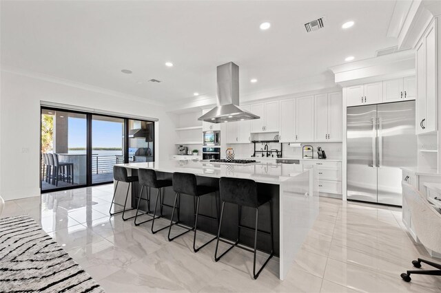 kitchen with visible vents, ornamental molding, island range hood, light countertops, and built in appliances