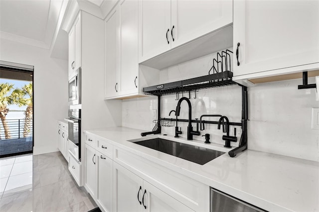 kitchen with white cabinetry, light countertops, appliances with stainless steel finishes, and a sink