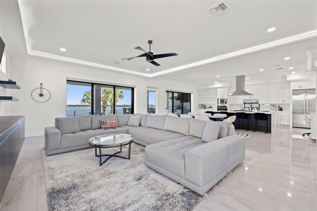 living room featuring visible vents, ceiling fan, recessed lighting, marble finish floor, and a raised ceiling