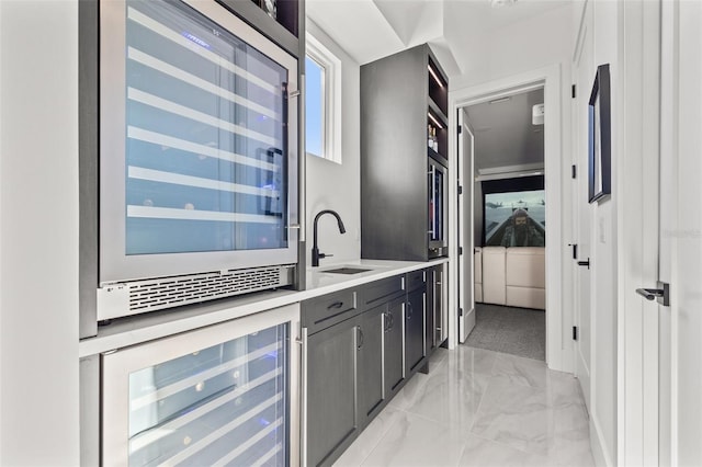 bar with a sink, marble finish floor, and beverage cooler