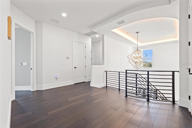 empty room with visible vents, dark wood-type flooring, baseboards, recessed lighting, and an inviting chandelier