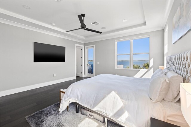 bedroom featuring ornamental molding, a ceiling fan, a tray ceiling, dark wood finished floors, and baseboards