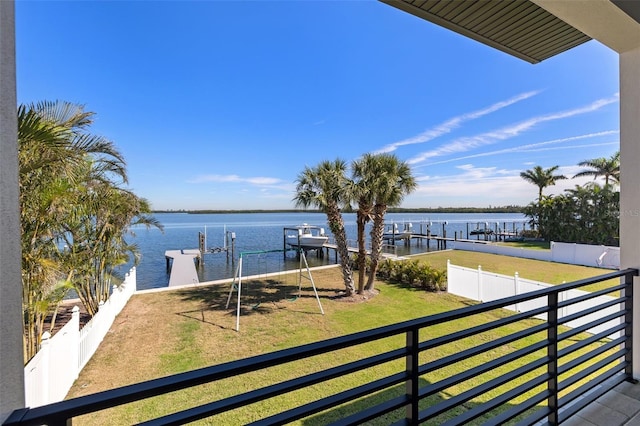 exterior space with fence, a water view, a lawn, a balcony, and boat lift