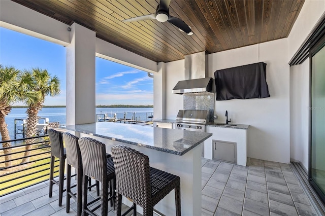 view of patio featuring a water view, area for grilling, a grill, a ceiling fan, and a sink