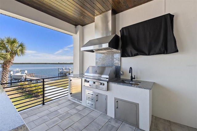 view of patio / terrace featuring a water view, exterior kitchen, a balcony, area for grilling, and a sink