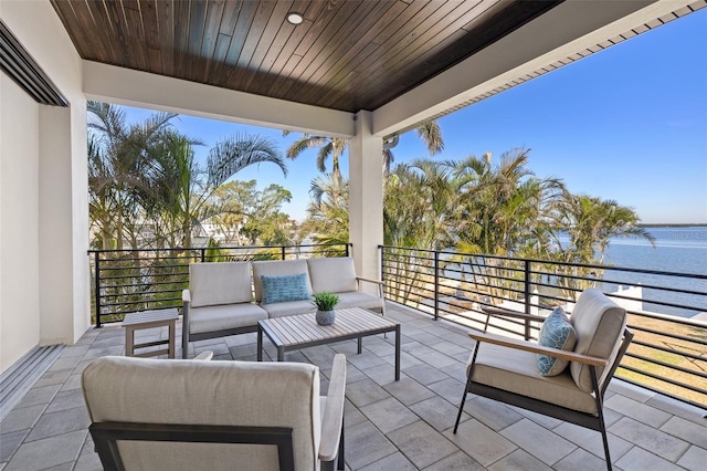 view of patio with an outdoor living space, a balcony, and a water view