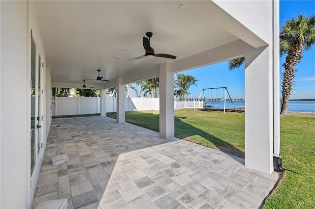 view of patio featuring fence, a ceiling fan, and a water view