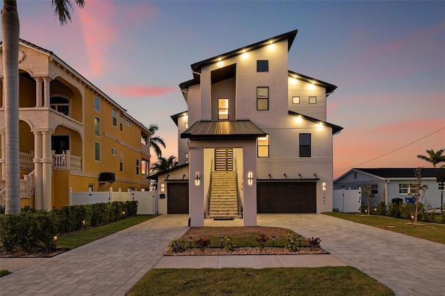 modern home with a standing seam roof, stucco siding, stairs, decorative driveway, and metal roof