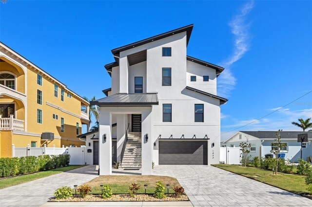 contemporary home with stucco siding, a standing seam roof, decorative driveway, stairway, and metal roof