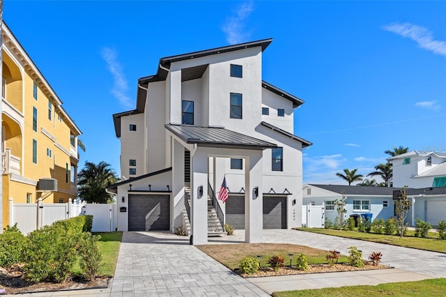 contemporary home with stucco siding, a standing seam roof, metal roof, decorative driveway, and a garage