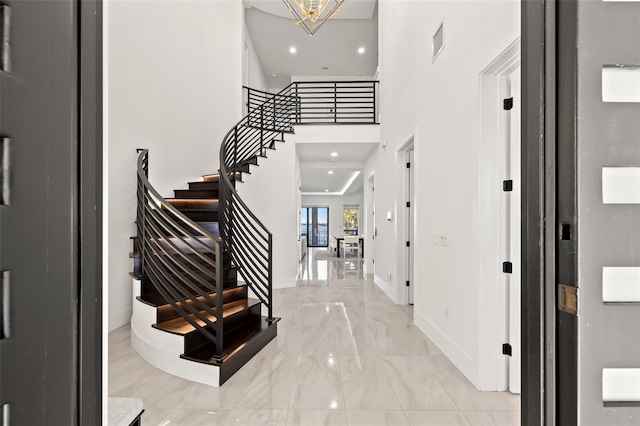 foyer entrance with stairway, a high ceiling, marble finish floor, baseboards, and visible vents