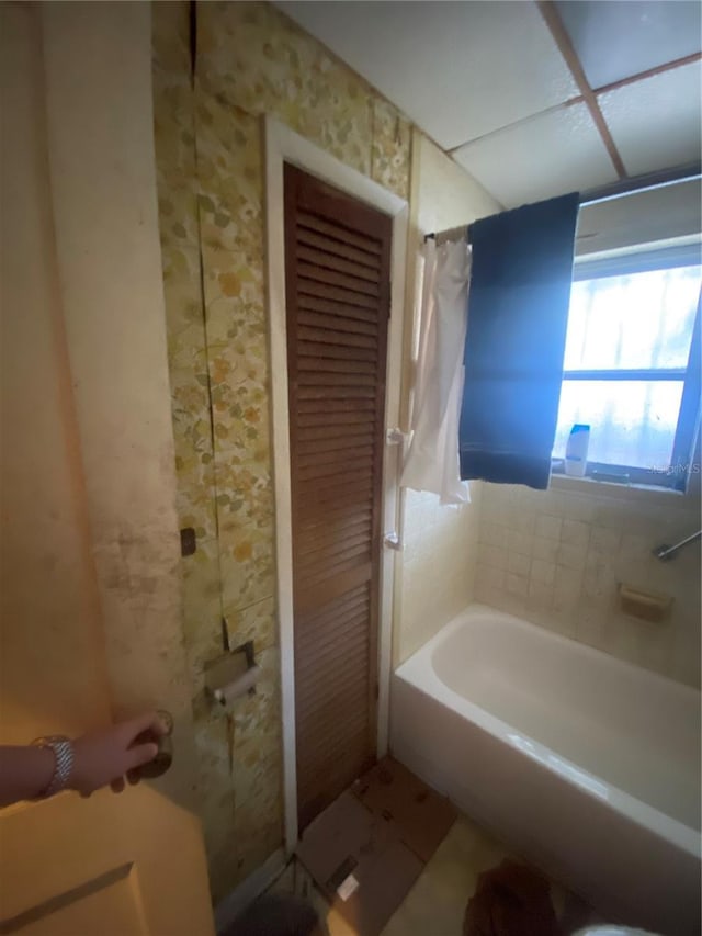 full bathroom featuring wallpapered walls and shower / bath combo