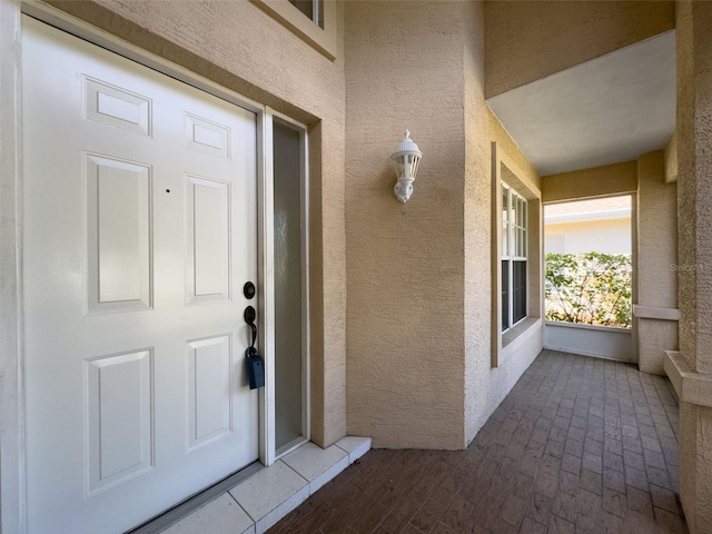 doorway to property with a porch and stucco siding