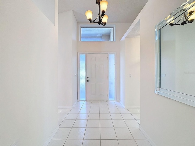 foyer entrance with a chandelier, baseboards, and light tile patterned floors