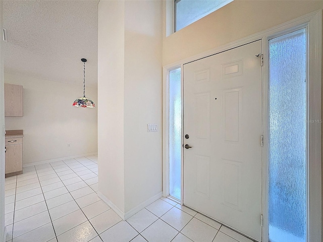 entryway featuring a textured ceiling, baseboards, and light tile patterned floors